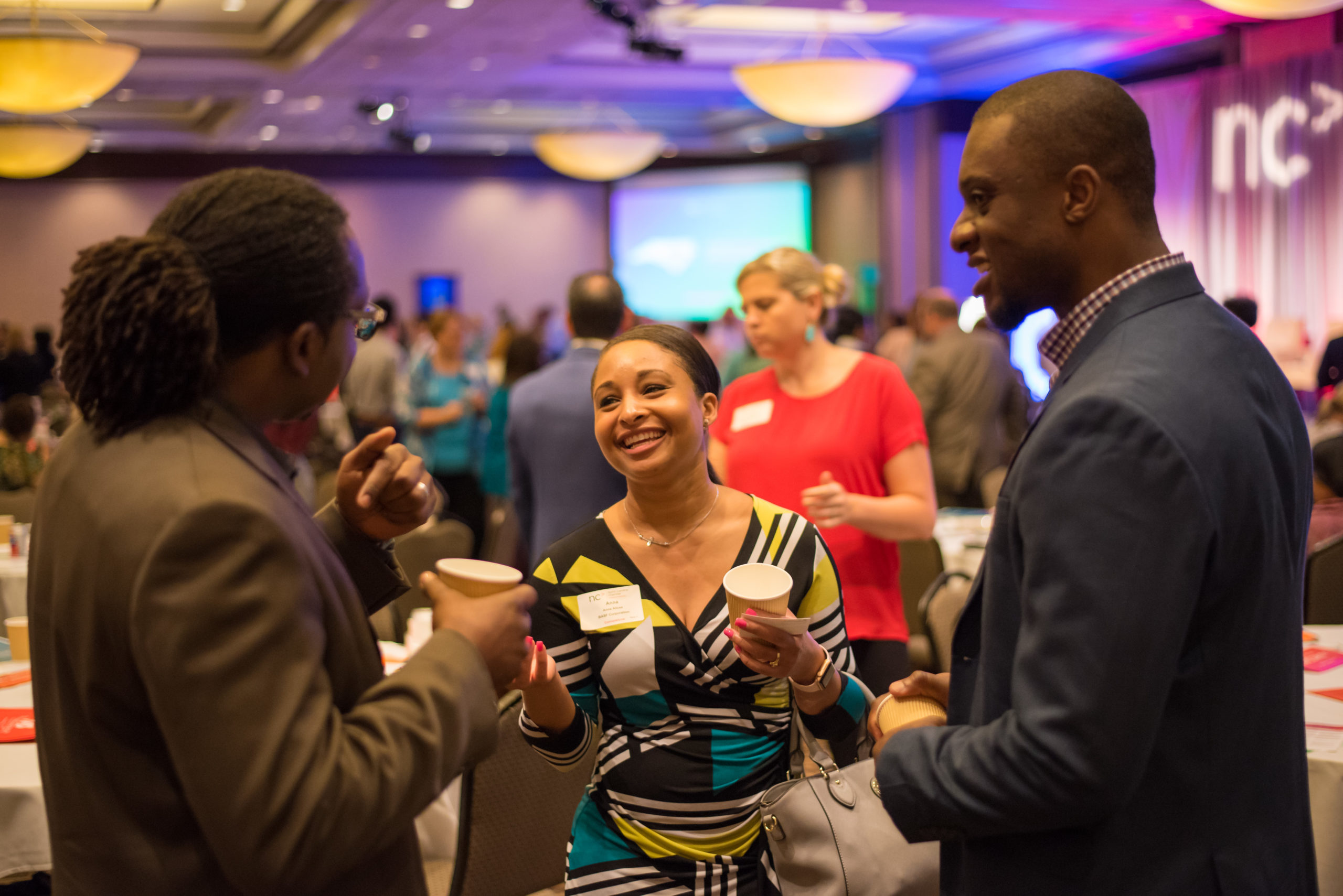 Three conference attendees smiling and talking